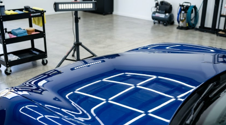 Close-up of high-intensity specialized LED lighting revealing paint reflection on a blue Porsche bonnet at Next Car Detail workshop