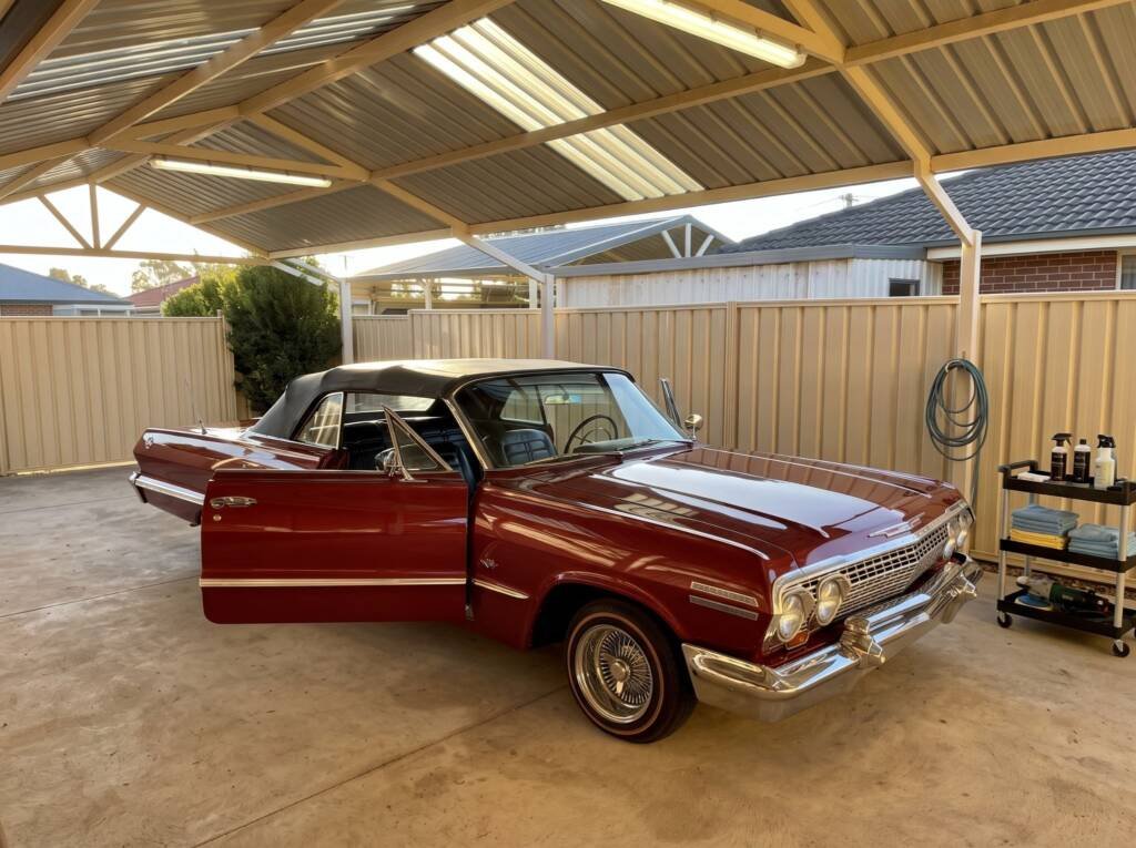 A classic red Chevrolet convertible parked under a carport before detailing.